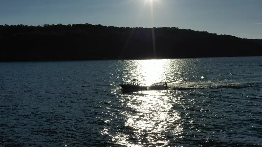 A distant boat towing a rider through reflected sunlight